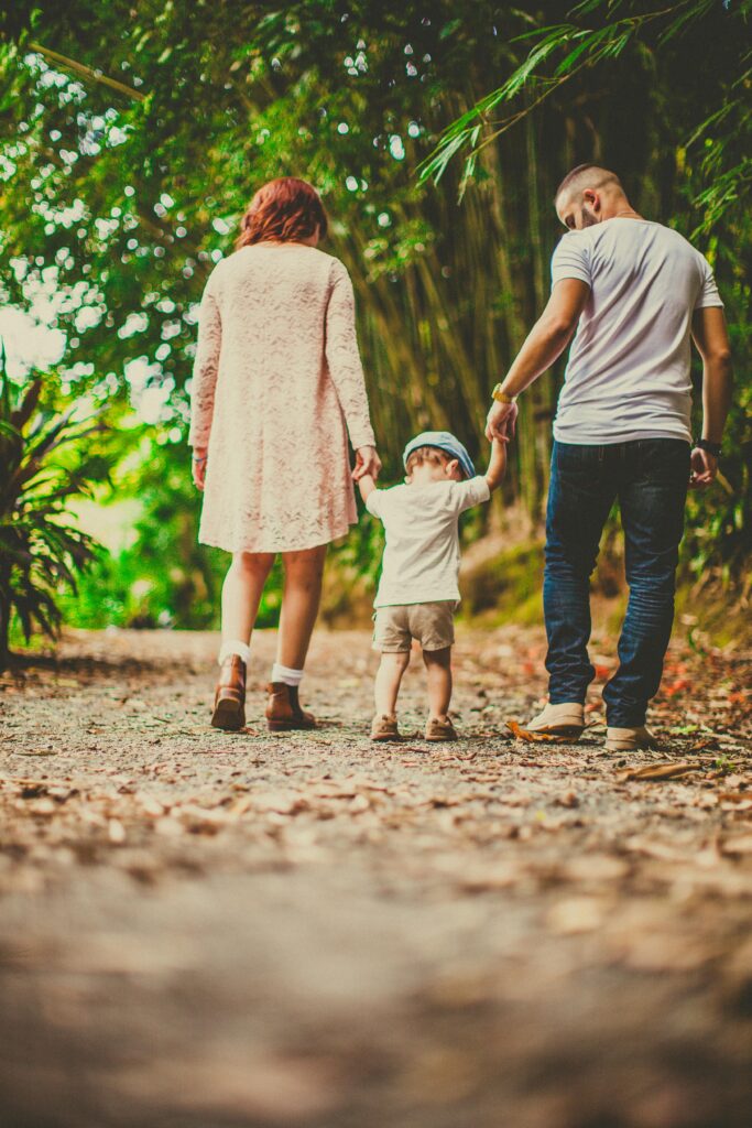 pexels photo 3038455 3038455 A family enjoys a leisurely walk in a green park, embodying joy and togetherness.