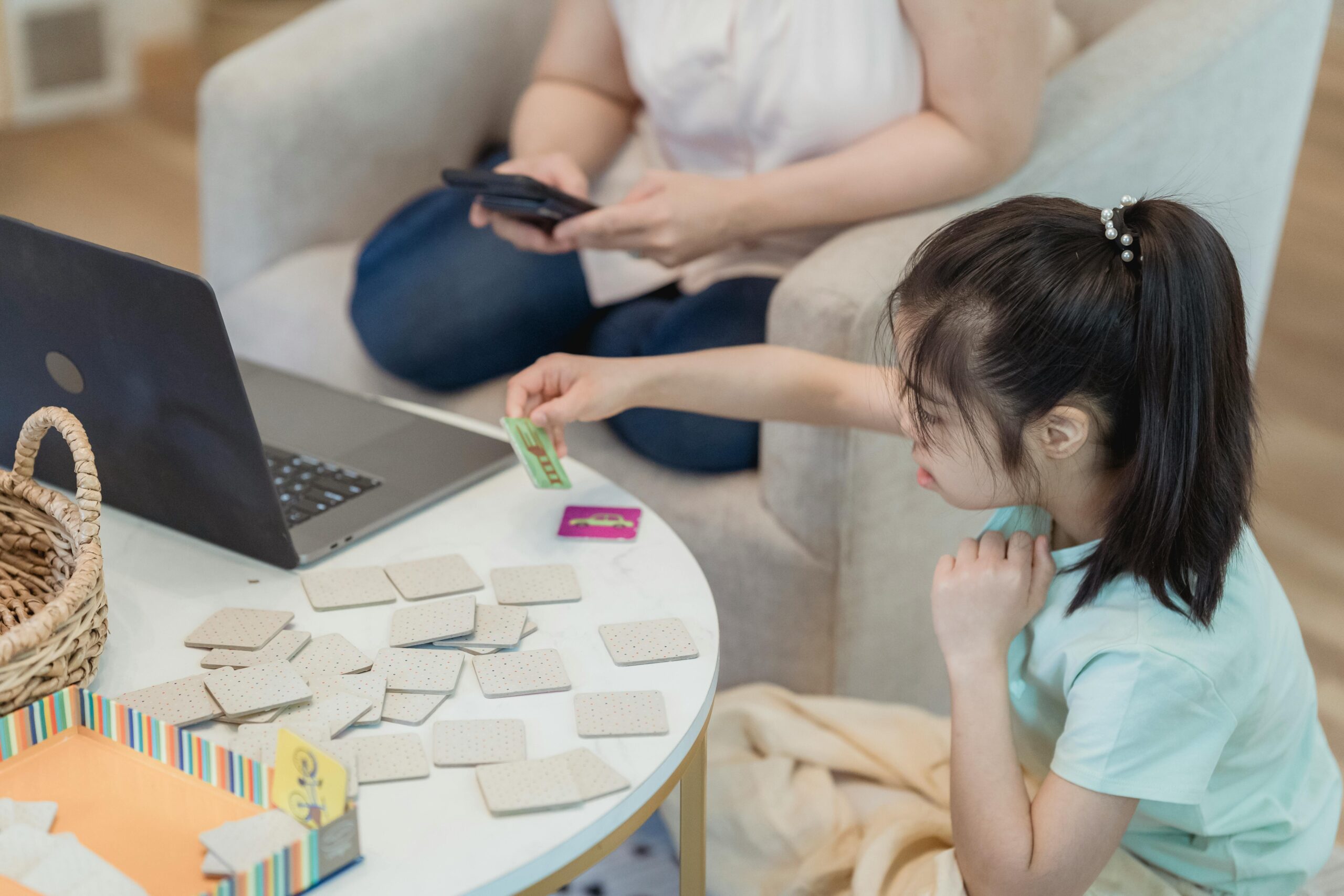 🧠 15 Brain-Boosting Games for Kids at Home Asian girl focused on memory game at home with cards, enhancing cognitive skills.